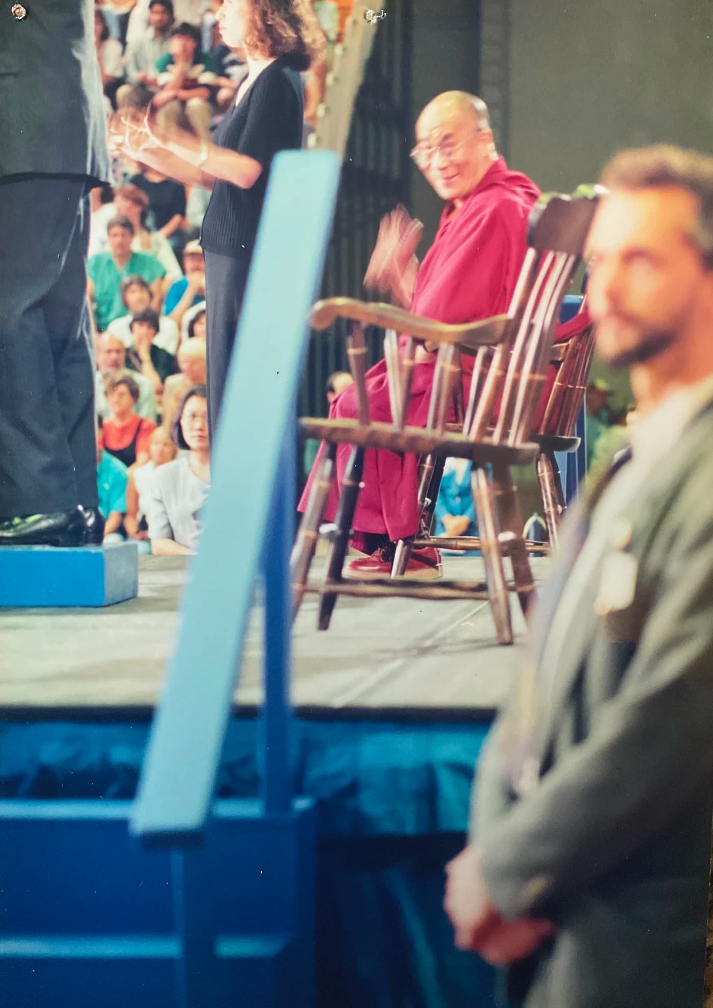 Allen Pittman standing in the foreground while the Dalai Lama sits on stage behind him